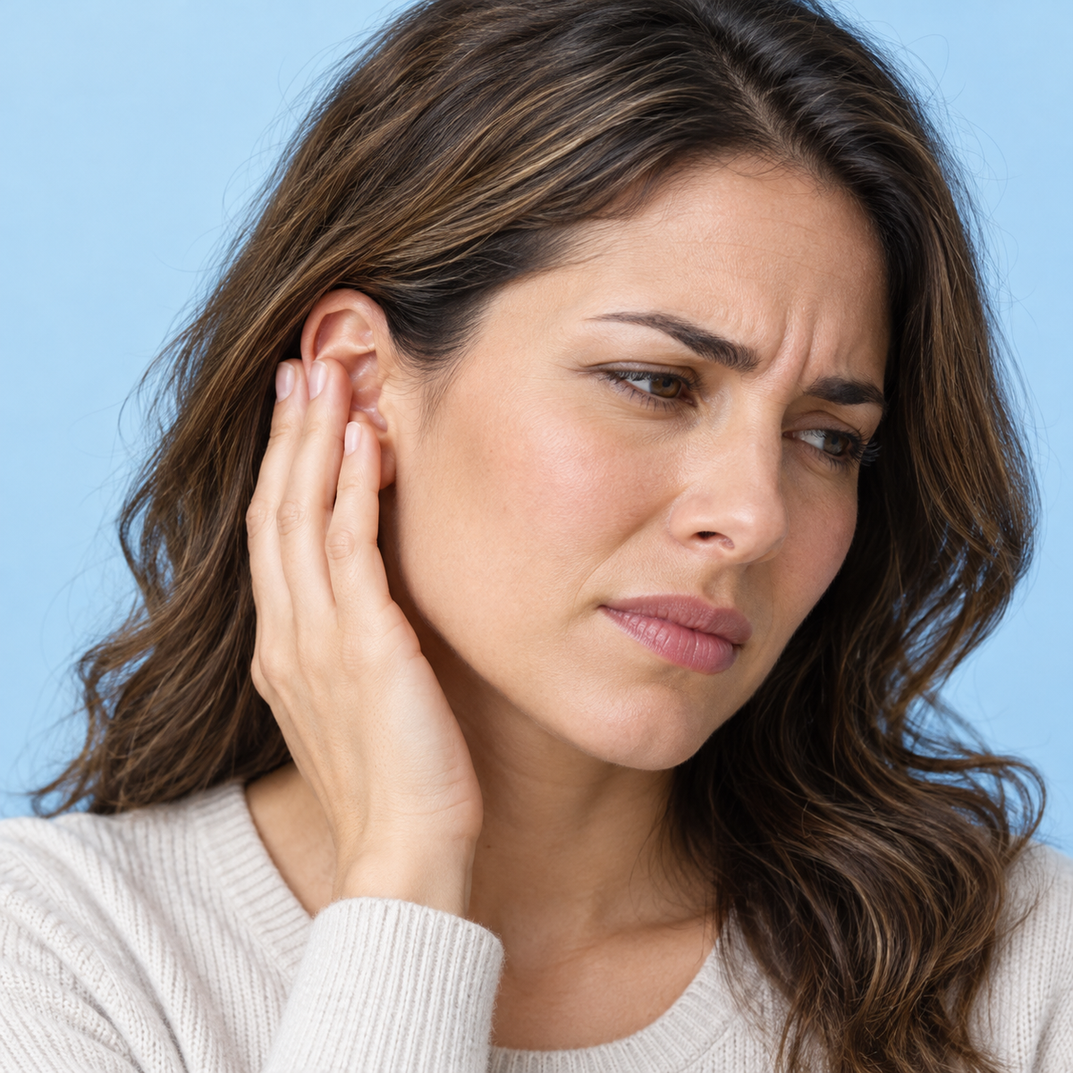 Adult touching the outer ear to illustrate ear discomfort
